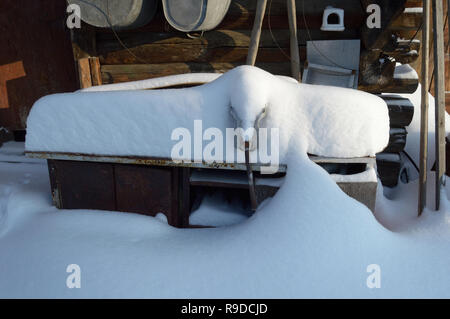 Kovrov, la Russie. 23 janvier 2016. Table de travail avec un vice de neige en face de l'ancienne grange dans la cour d'une maison en bois de plain pied Banque D'Images