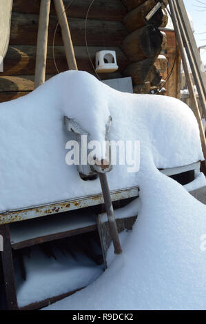 Kovrov, la Russie. 23 janvier 2016. Table de travail avec un vice de neige en face de l'ancienne grange dans la cour d'une maison en bois de plain pied Banque D'Images