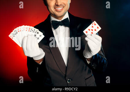 Showman professionnel portant costume et gants blancs isolés sur fond rouge et noir joyeux sourire close-up Banque D'Images