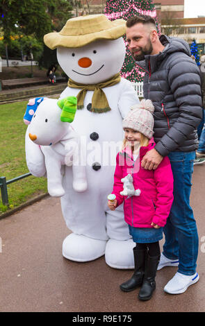 Bournemouth, Royaume-Uni. 23 décembre 2018. Le Bonhomme et Snowdog visiter Bournemouth, illuminant un jour de bruine gris comme file d'enfants avec excitation d'avoir leur photo prise avec eux dans Jardins de Bournemouth. Fille et de l'homme posent avec le Bonhomme de neige. L'arbre de Varsovie, une partie de l'arbre de Noël de Bournemouth Wonderland en arrière-plan. Credit : Carolyn Jenkins/Alamy Live News Banque D'Images