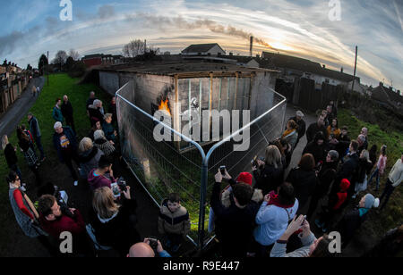 Les gens se rassemblent autour de clôtures érigés pour protéger le dernier dessin de l'artiste Banksy sur un mur de garage dans la région de Port Talbot Taibach en Galles du Sud. Banque D'Images