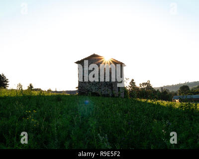 Cabane en pierre solitaire, paisible sur un pré au lever du soleil Banque D'Images