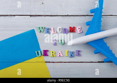 Temps de voyage - Lettres en bois coloré avec du texte 'Bienvenue à l'Ukraine" , pavillon de l'Ukraine, modèle d'avion, Passeport on white background Banque D'Images