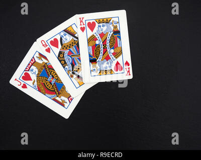 Poker, jeu de cartes français, chiffres : Jack, reine, roi de cœur, sur une surface en ardoise noire Banque D'Images