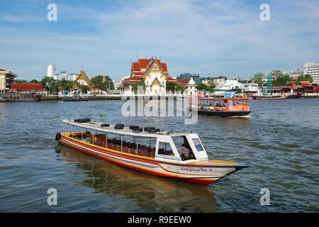 Un bateau de tourisme (avant) et une rivière ferry (arrière) sur la rivière Chao Phraya, Bangkok, Thaïlande ; en arrière-plan temple Wat Rakhang Banque D'Images