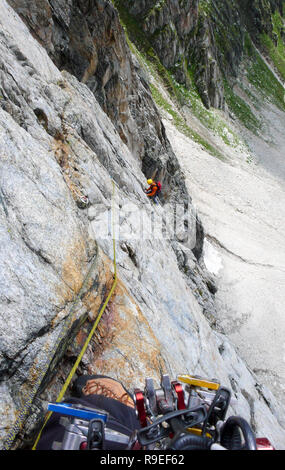 Rock climber sur un disque itinéraire alpin dans les Alpes de Suisse en plaçant la protection mobile Banque D'Images