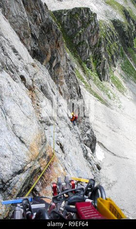 Rock climber sur un disque itinéraire alpin dans les Alpes de Suisse en plaçant la protection mobile Banque D'Images