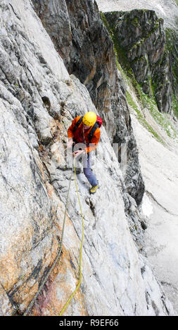 Rock climber sur un disque itinéraire alpin dans les Alpes de Suisse en plaçant la protection mobile Banque D'Images