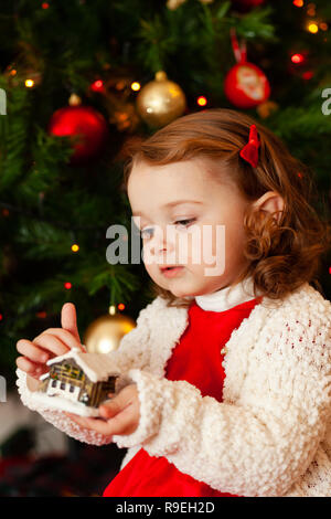 Portrait d'un beau petit enfant avec robe rouge près de l'arbre de Noël. Banque D'Images