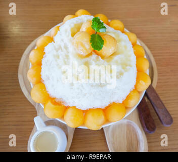 Corée style Bingsu dessert / bingsu bingsoo cantaloup bac sur table en bois - desserts sucrés fruits melon cantaloup rasée coréen sur la glace topping avec mil Banque D'Images