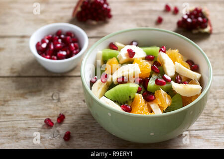 Salade de tranches de divers fruits et graines de grenade sur un fond de bois. Focus sélectif. Banque D'Images