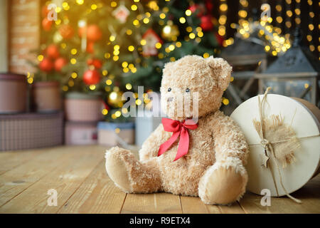 Les nounours de l'emplacement sous l'arbre de Noël avec des cadeaux. Maison de l'arrière-plan. Lumières de Noël Banque D'Images