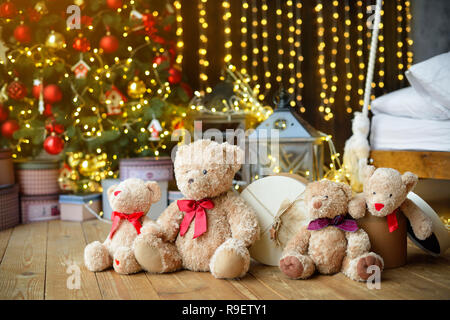 Famille d'ours de l'emplacement sous l'arbre de Noël avec des cadeaux. Maison de l'arrière-plan. Lumières de Noël Banque D'Images