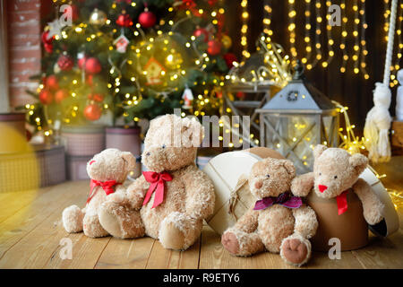 Famille d'ours de l'emplacement sous l'arbre de Noël avec des cadeaux. Maison de l'arrière-plan. Lumières de Noël Banque D'Images