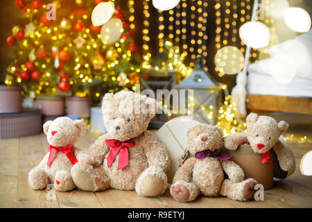 Famille d'ours de l'emplacement sous l'arbre de Noël avec des cadeaux. Maison de l'arrière-plan. Lumières de Noël Banque D'Images