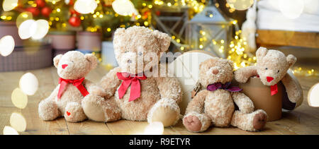 Famille d'ours de l'emplacement sous l'arbre de Noël avec des cadeaux. Maison de l'arrière-plan. Lumières de Noël Banque D'Images