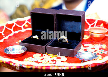 Boîte avec une bague de mariage en or avec un diamant est dans les pétales de roses rouges Banque D'Images