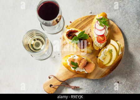 Antipasti italiens des en-cas pour le vin. Brushetta avec fromage, poire, radis, le saumon et les tomates séchées sur un fond noir en lumière. Vue supérieure de la télévision Banque D'Images