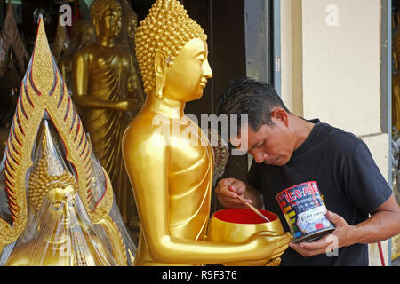 Un artisan à un atelier à Bamrung Muang Road, Bangkok, Thaïlande, mettant la touche finale à une statue représentant Bouddha comme un moine avec un bol d'aumône" Banque D'Images