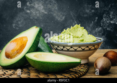 Guacamole fait maison et des matières d'avocats sur un fond de bois. La cuisine mexicaine Banque D'Images