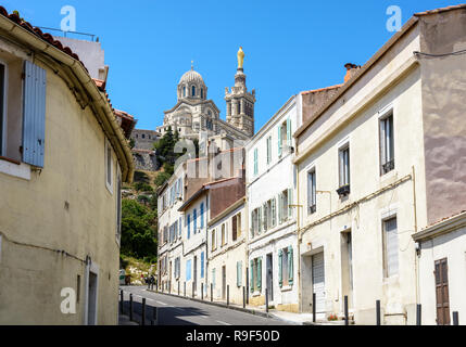 Une étroite rue en pente bordée de maisons anciennes à Marseille, France, allant jusqu'à Notre-Dame de la garde en haut de la colline. Banque D'Images