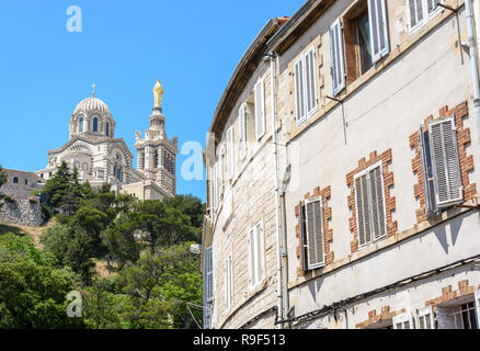 Vue arrière de la basilique Notre-Dame de la garde en haut de la colline à Marseille, France, vu de la rue ci-dessous avec de vieilles maisons en premier plan Banque D'Images