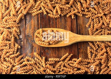 Vue de dessus de l'ensemble des pâtes Fusilli avec cuillère en bois, sur un fond de bois. copy space Banque D'Images