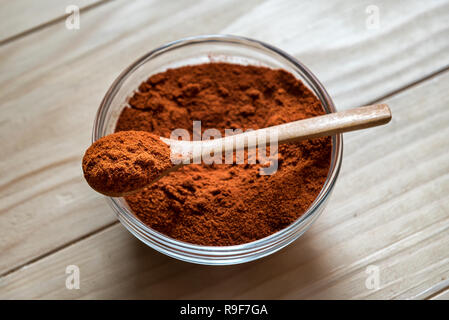 Paprika en poudre sur la cuillère en bois, dans un bol en verre sur une table en bois Banque D'Images