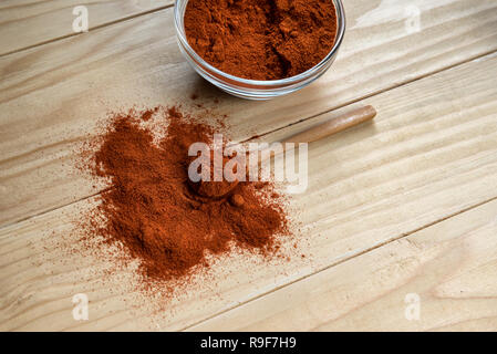 Paprika en poudre sur la cuillère en bois, dans un bol en verre sur une table en bois Banque D'Images