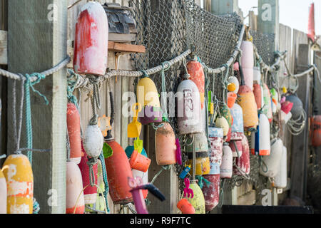 Bateaux de pêche et des bouées et des jouets suspendus à des cordes sur une clôture en bois. Banque D'Images