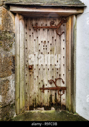 Vieille porte en bois situé dans mur de pierre, avec des charnières rouillées et poignée. Banque D'Images