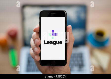 Un homme se penche sur son iPhone qui affiche le logo de la Ligue (usage éditorial uniquement). Banque D'Images