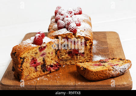 Des gâteaux à la framboise et chocolat blanc sur la table en bois. Diagramme circulaire décoré de petits fruits et saupoudrer de sucre en poudre. Deux pièces se trouve en face Banque D'Images