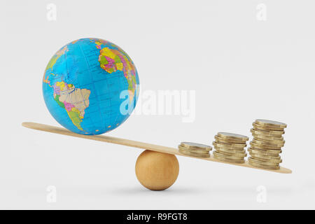 Globe terrestre et de l'échelle d'équilibre de la pile de pièces - Concept de la croissance économique la priorité sur la santé planétaire Banque D'Images