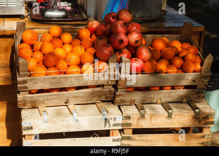 Cartons pleins d'oranges et de grenadiers sont vendus sur le marché. Le commerce de rue dans des fruits frais. Banque D'Images