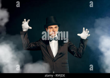 Le port de gants combinaison professionnelle showman et top hat standing isolé sur fond bleu et noir des gestes atmosphère mystérieuse Banque D'Images