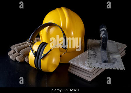 Outils pour maçon et casque sur un tableau noir. Accessoires pour les travailleurs de la construction. Fond sombre. Banque D'Images