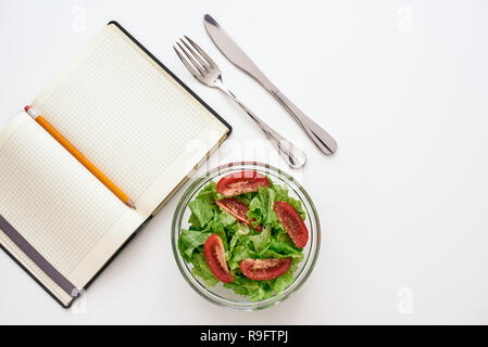 La préparation d'aliments sains. Vue de dessus du livre de recette, Salade à proximité, isolé. Fourchette et couteau près de la plaque Banque D'Images