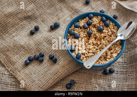 Prêt à manger. Vue de dessus de la saine et utile des céréales de petit-déjeuner avec des bleuets, de l'avoine dans un bol sur l'isolé. Une collation ou un petit-déjeuner le matin. Cuillère en métal dans du muesli Banque D'Images