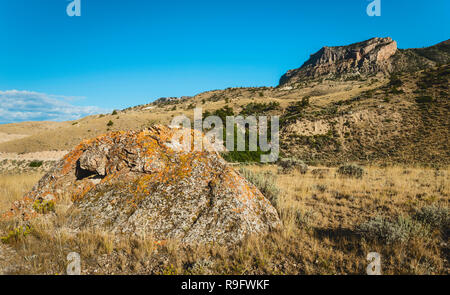 Le paysage aride de la prairie bordée de rochers et les contreforts des Rocheuses sur une belle journée d'été près de Cody, Wyoming, USA. Banque D'Images