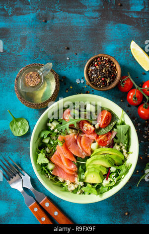 Menu de régime, la nourriture végétalienne. Salade saine avec le quinoa, la roquette, les tomates, le saumon et d'avocat en béton ou en pierre bleue sur la table. Vue supérieure de la télévision mise de fond. Banque D'Images