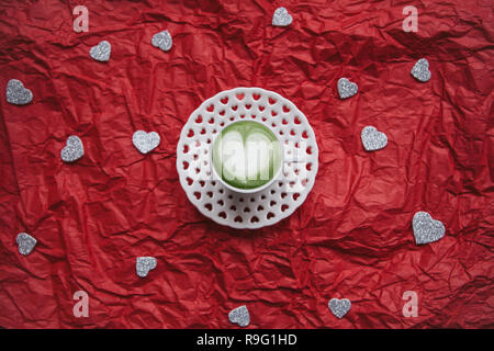 Frais vert matcha café avec un motif coeur sur un arrière-plan de fête avec beaucoup de cœurs. Concept pour la Saint Valentin ou la Journée de la femme. Banque D'Images