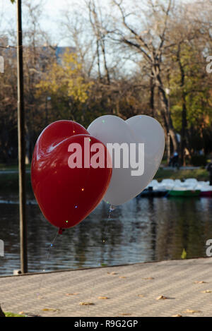 Ballons rouges et blancs sous la forme d'un coeur. lié avec des bandes de feux lumineux Banque D'Images