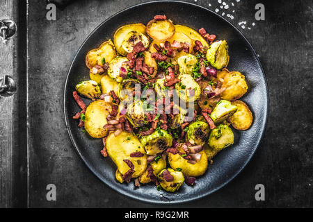 Pommes de terre sautées avec les choux de Bruxelles et le bacon sur une assiette Banque D'Images