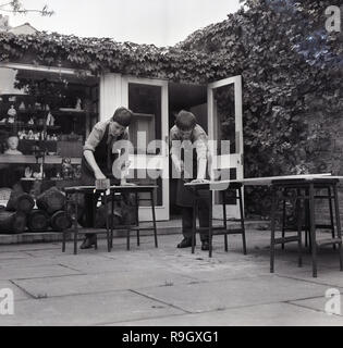 1968, le sud de Londres, un centre-ville garçons boarding school, en Angleterre, deux collégiens de faire le travail du bois à l'extérieur, sur le patio, England, UK. Banque D'Images