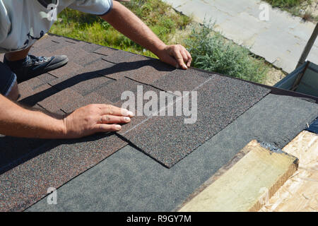 L'installation de couvreur bardeaux d'asphalte sur la construction d'une maison d'angle de toiture. Construction de toiture. Couvreur pose des tuiles du toit. Banque D'Images