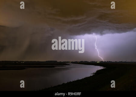 Ciel Omnious et puissant coup de foudre avec un arbre de pluie à gauche près d'un lac en Hollande. Photographié au cours d'une tempête chase, près de Rotterdam. Banque D'Images