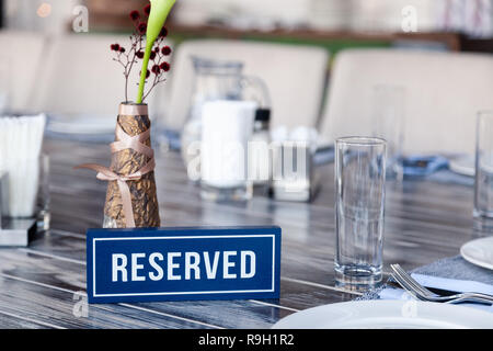 En gros plan bleu blanc plaque rectangulaire avec le mot réservés debout sur table vintage gris dans restaurant proche de réglage, serviettes, sel poivre, Banque D'Images