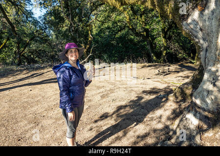 Une fille en bleu et violet Hat Prendre des photos avec un téléphone à l'extérieur dans une zone forestière, Fédération de Ridge OSP, Californie Banque D'Images