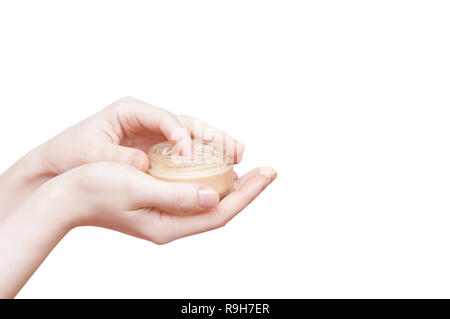 Mains d'une fille avec un pot de crème pour le visage de près. Isoler blanc Banque D'Images